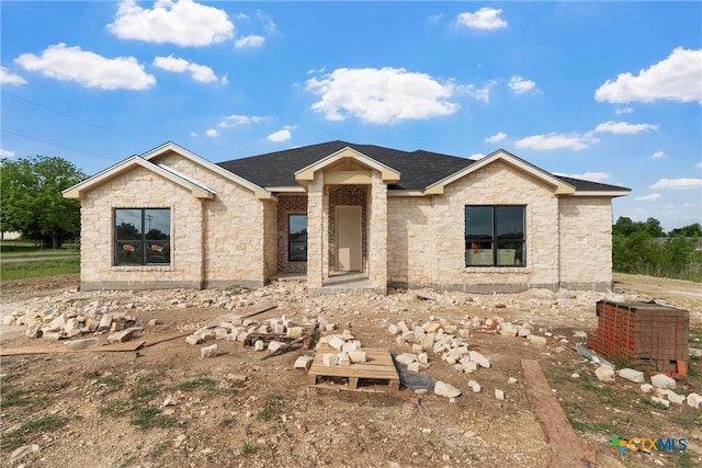 view of front of property with roof with shingles and stone siding