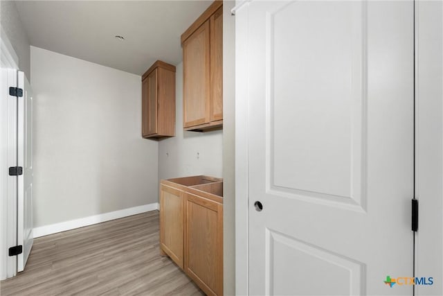 laundry area featuring baseboards and light wood-style flooring