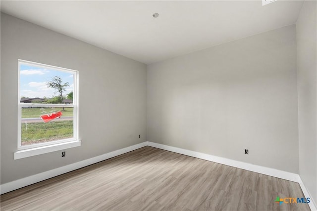 spare room with baseboards and wood finished floors