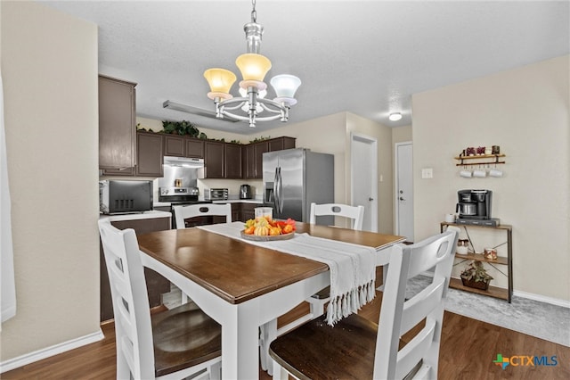 dining space with a textured ceiling, a notable chandelier, and dark hardwood / wood-style floors