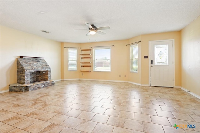 4409 Beach Ball Dr, Killeen, TX 76549 - unfurnished living room with ceiling fan, healthy amount of natural light, a textured ceiling, a stone fireplace, and baseboards