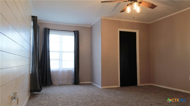 carpeted spare room featuring ceiling fan, baseboards, and crown molding