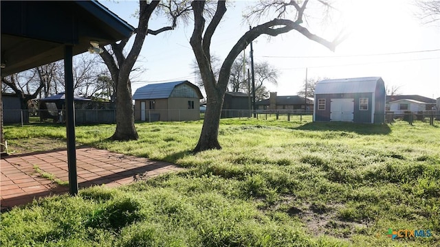 view of yard featuring a storage shed, a fenced backyard, a residential view, an outbuilding, and a patio area