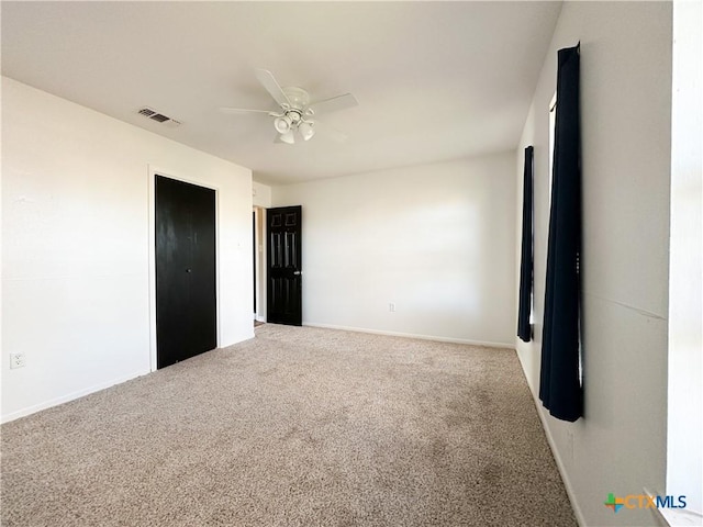 unfurnished bedroom featuring carpet, visible vents, ceiling fan, and baseboards