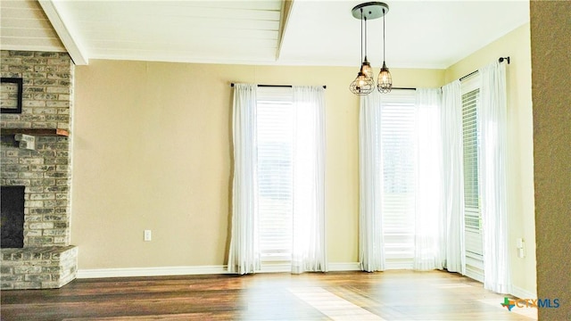 interior space featuring a brick fireplace, baseboards, wood finished floors, and beamed ceiling