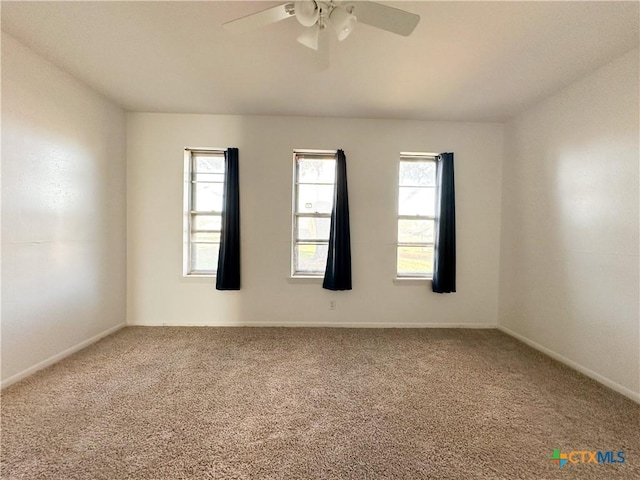 carpeted empty room with a ceiling fan and baseboards