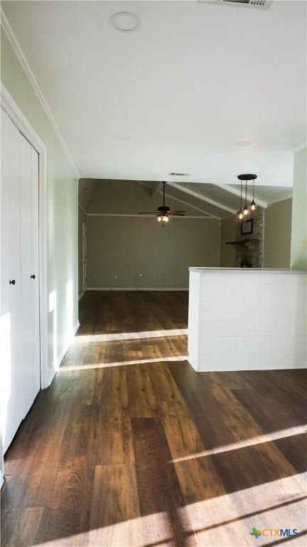 hallway featuring lofted ceiling, visible vents, ornamental molding, and wood finished floors