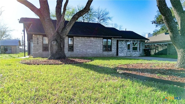 rear view of property featuring fence, a lawn, and brick siding