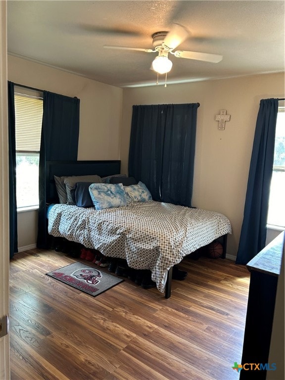 bedroom featuring ceiling fan, wood-type flooring, and multiple windows