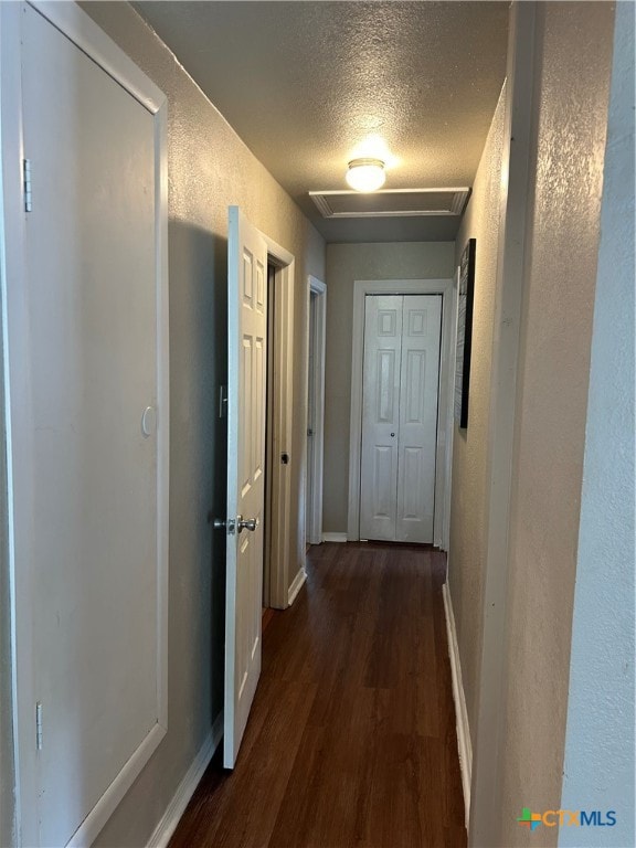 corridor with dark hardwood / wood-style flooring and a textured ceiling