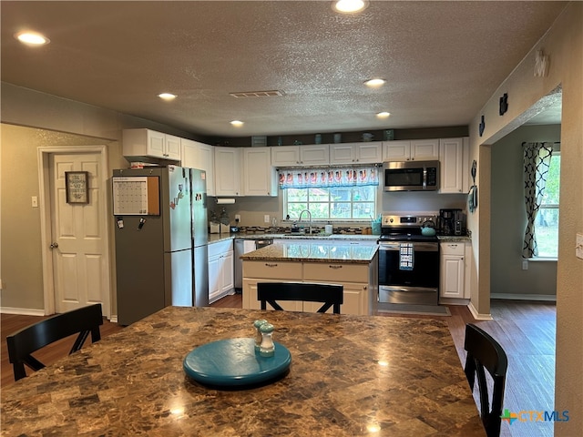 kitchen with white cabinetry, appliances with stainless steel finishes, dark wood-type flooring, and stone countertops