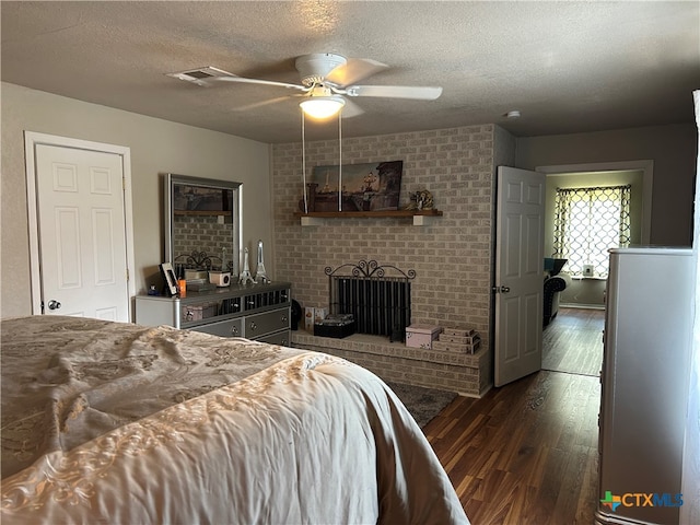 bedroom featuring ceiling fan, a textured ceiling, dark hardwood / wood-style floors, and a fireplace