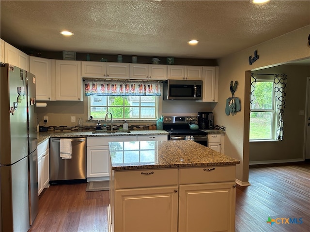 kitchen featuring white cabinets, stainless steel appliances, hardwood / wood-style flooring, and a kitchen island