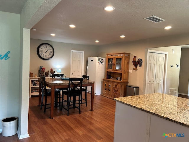 dining area featuring dark wood-type flooring and a textured ceiling