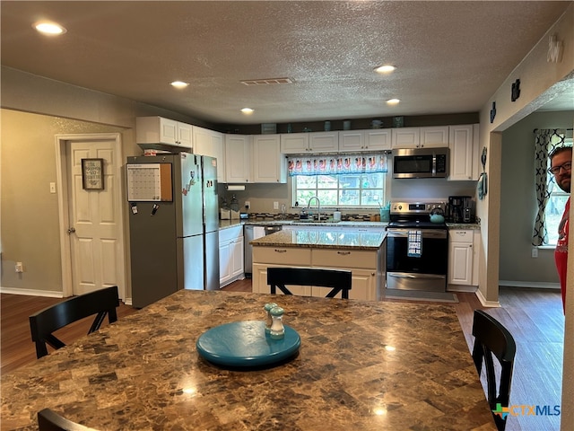 kitchen with white cabinets, stainless steel appliances, and dark hardwood / wood-style flooring