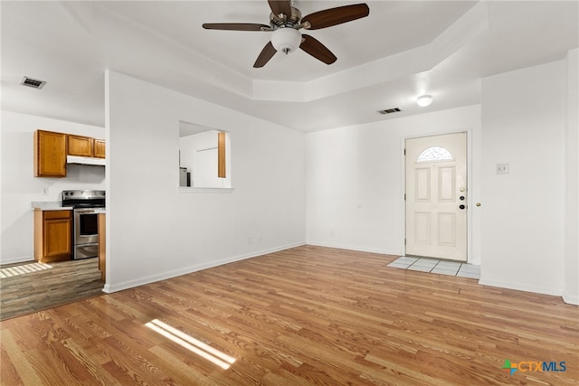 entryway featuring a tray ceiling, ceiling fan, and light wood-type flooring