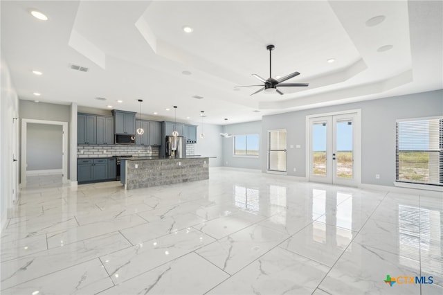 unfurnished living room with ceiling fan and a raised ceiling