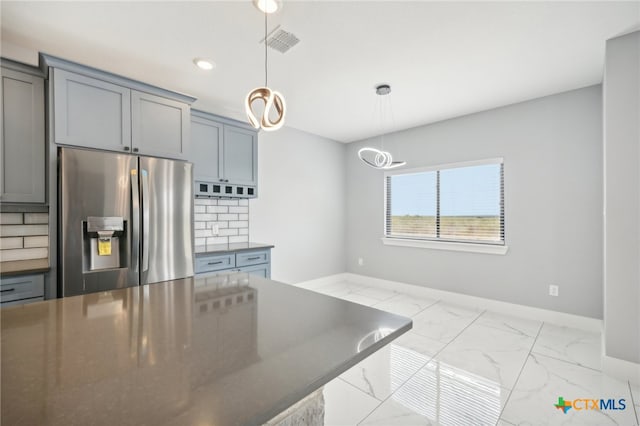 kitchen with tasteful backsplash, hanging light fixtures, stainless steel refrigerator with ice dispenser, and an inviting chandelier