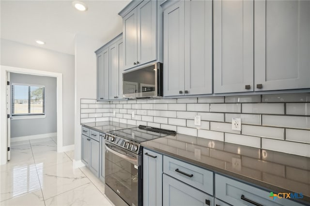 kitchen featuring appliances with stainless steel finishes, dark stone counters, tasteful backsplash, and gray cabinetry