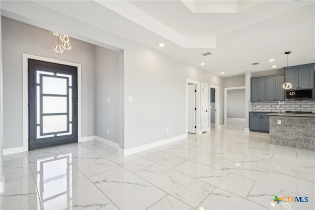 kitchen featuring gray cabinetry, decorative light fixtures, a chandelier, and tasteful backsplash