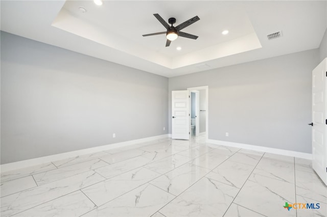 spare room with a tray ceiling and ceiling fan