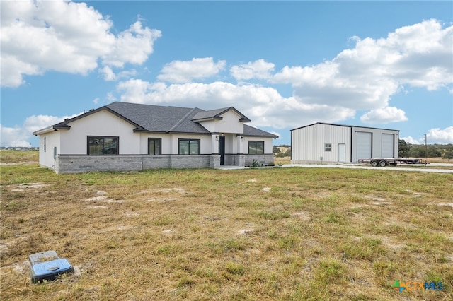 view of front of home featuring a garage, a front lawn, and an outdoor structure