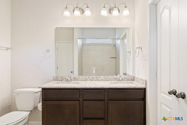 bathroom with tiled shower, vanity, and toilet