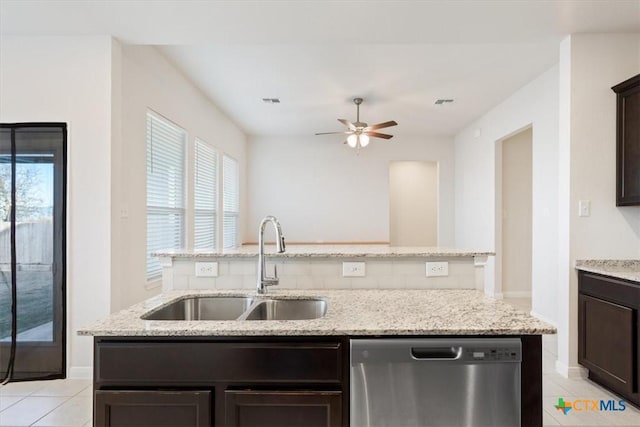 kitchen with stainless steel dishwasher, light tile patterned floors, sink, and a center island with sink