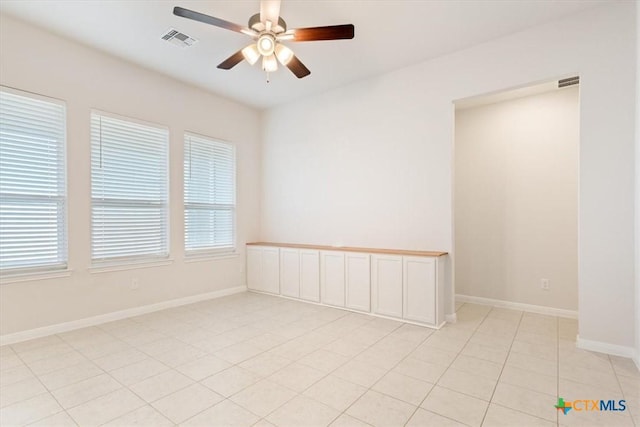 tiled empty room featuring ceiling fan