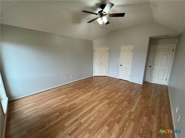 unfurnished bedroom with light wood-style floors, a ceiling fan, vaulted ceiling, and a textured ceiling