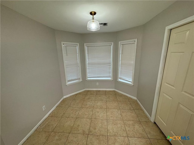 empty room featuring visible vents, baseboards, and light tile patterned floors