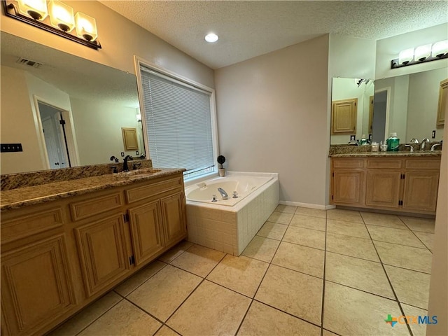 bathroom with tile patterned flooring, a textured ceiling, two vanities, and a sink