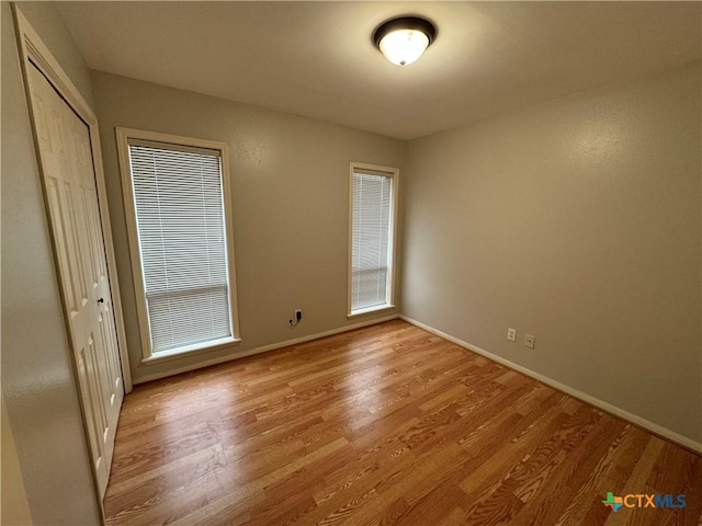 interior space featuring light wood-style floors, a closet, and baseboards