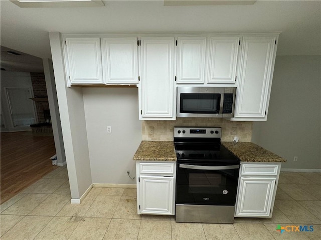 kitchen with light tile patterned floors, white cabinets, decorative backsplash, dark stone countertops, and stainless steel appliances