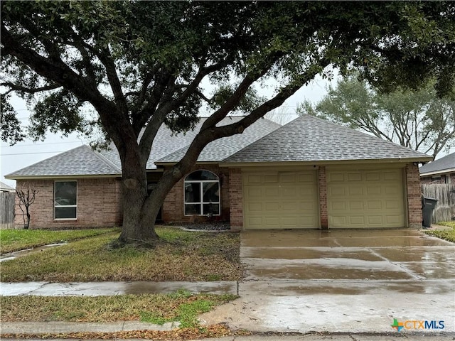 single story home with a garage, driveway, a shingled roof, and brick siding