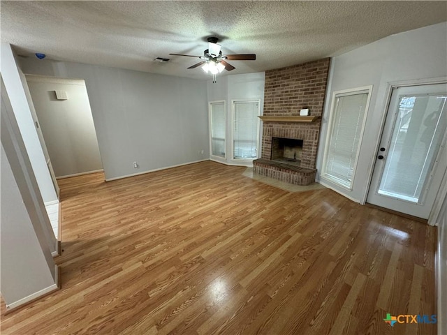 unfurnished living room with visible vents, a ceiling fan, a textured ceiling, light wood-style floors, and a fireplace