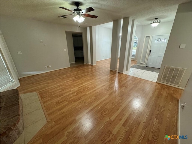 interior space featuring visible vents, baseboards, a ceiling fan, a textured ceiling, and light wood-style floors