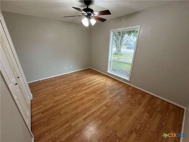 spare room with light wood-style floors, baseboards, and a ceiling fan