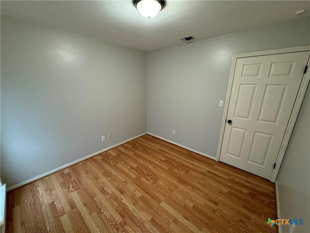 empty room featuring light wood finished floors, visible vents, and baseboards