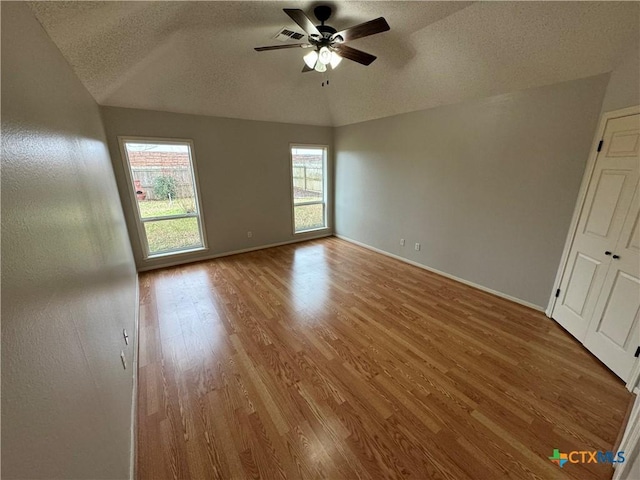 spare room with baseboards, visible vents, a ceiling fan, wood finished floors, and a textured ceiling