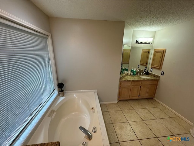 bathroom featuring a textured ceiling, tile patterned flooring, a garden tub, vanity, and baseboards