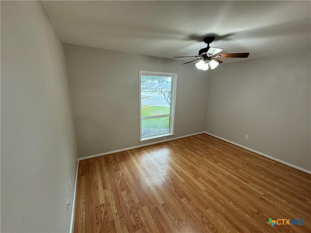 empty room featuring light wood finished floors, ceiling fan, and baseboards