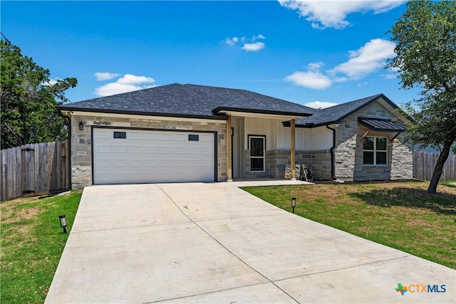 view of front of house with driveway, stone siding, fence, a front yard, and a garage