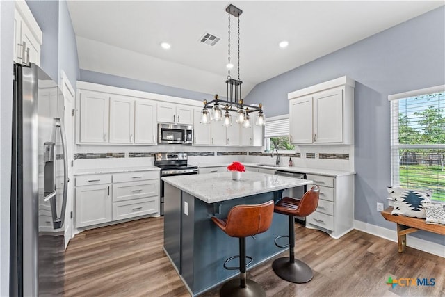 kitchen with a sink, decorative backsplash, appliances with stainless steel finishes, and wood finished floors