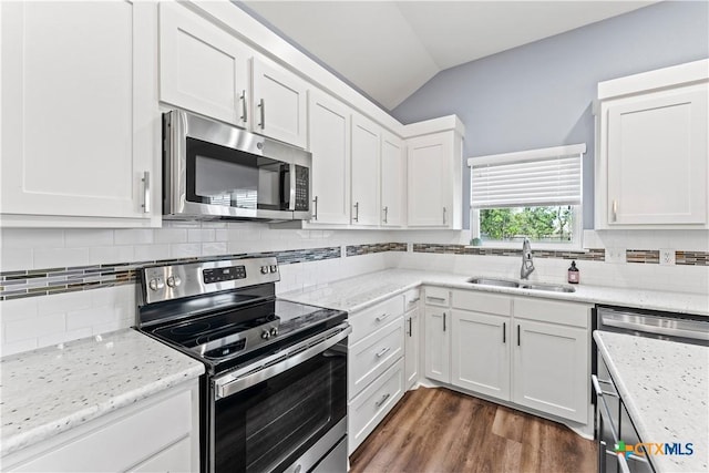 kitchen with vaulted ceiling, appliances with stainless steel finishes, dark wood-style floors, white cabinets, and a sink