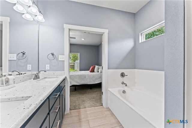 full bathroom with a sink, a garden tub, a healthy amount of sunlight, and double vanity