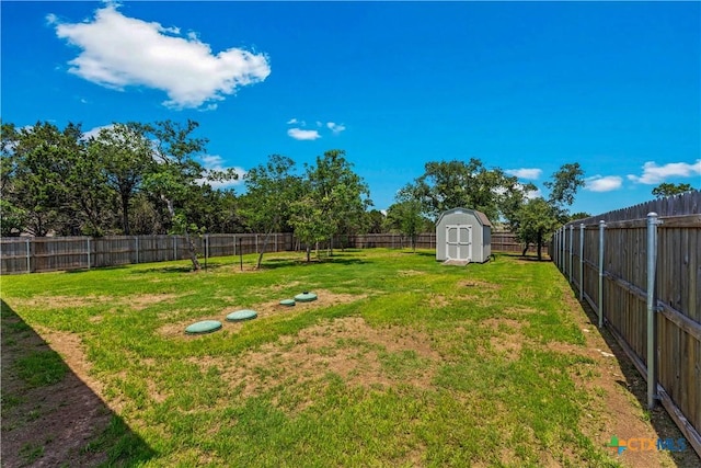 view of yard with an outdoor structure, a fenced backyard, and a shed