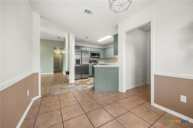 4408 Frontier Trl, Killeen, TX 76542 - kitchen with green cabinetry, stainless steel appliances, light countertops, light tile patterned floors, and a peninsula