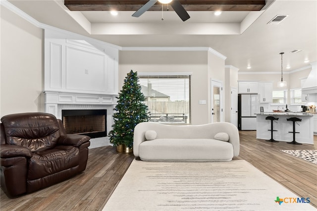 living room featuring a fireplace, dark hardwood / wood-style flooring, ceiling fan, and crown molding