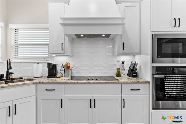 kitchen with white cabinets, sink, custom range hood, and stainless steel appliances